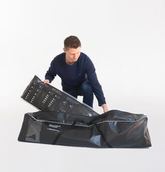 The man packs the folding gazebo side walls in the black side wall bag.